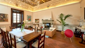 A spacious dining area with a wooden table and chairs, a fireplace, and a red chair. - Il Tosco (Montepulciano)