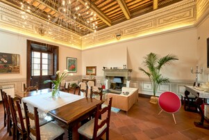 A spacious dining area with a wooden table and chairs, a fireplace, and a red chair.