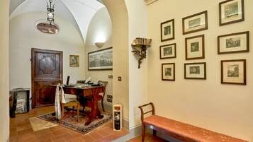 A hallway with a wooden bench, a desk with a computer, and a wall adorned with framed pictures.