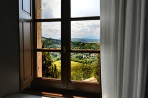 A window with a view of a green landscape and hills.