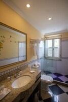 Un baño con un espejo grande, un lavabo, un inodoro y una zona de ducha.