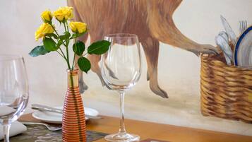 Une table à manger ornée d’un vase de roses jaunes, d’un verre et d’un panier contenant des couverts.