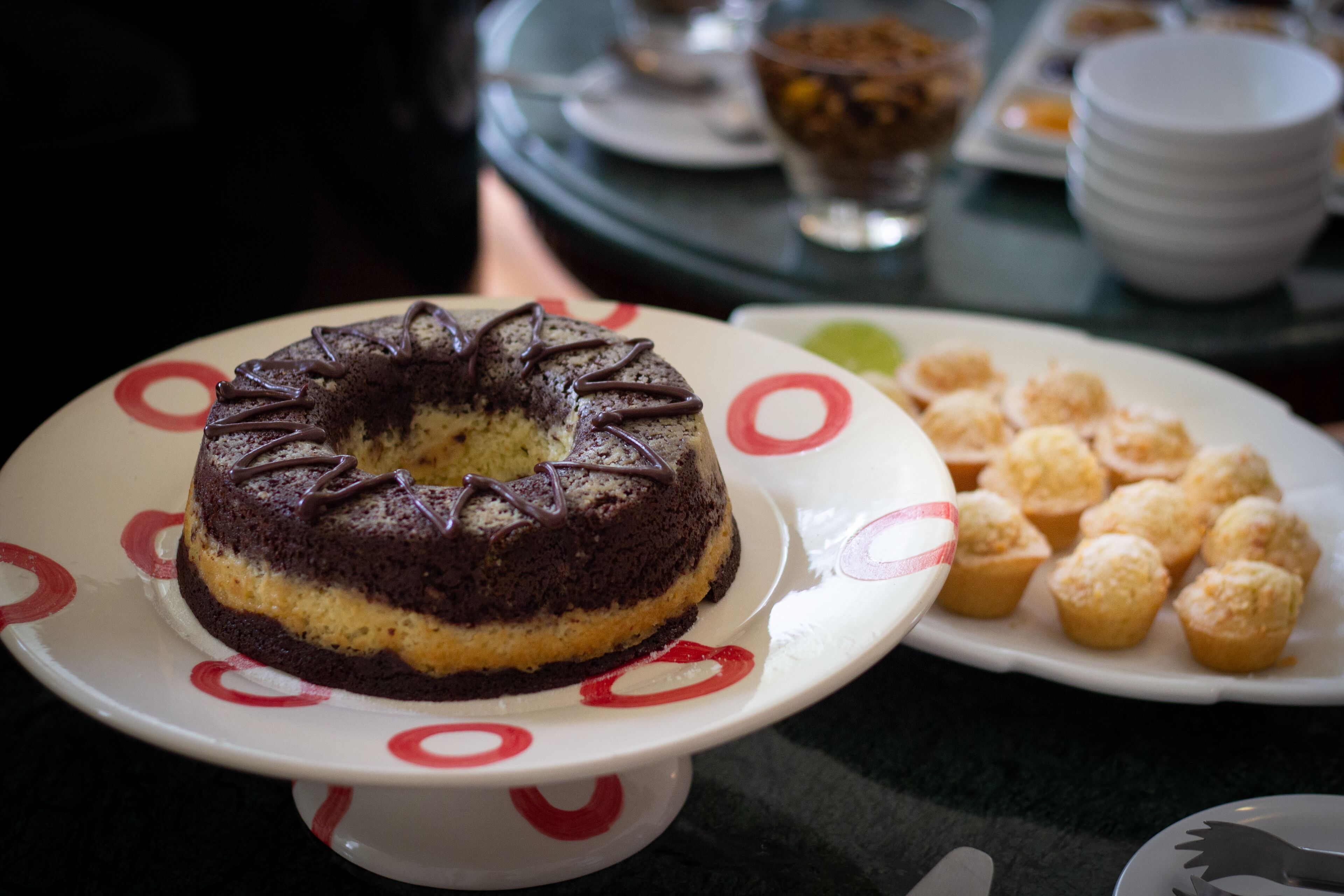 A chocolate cake with a yellow layer on a white plate with red designs.