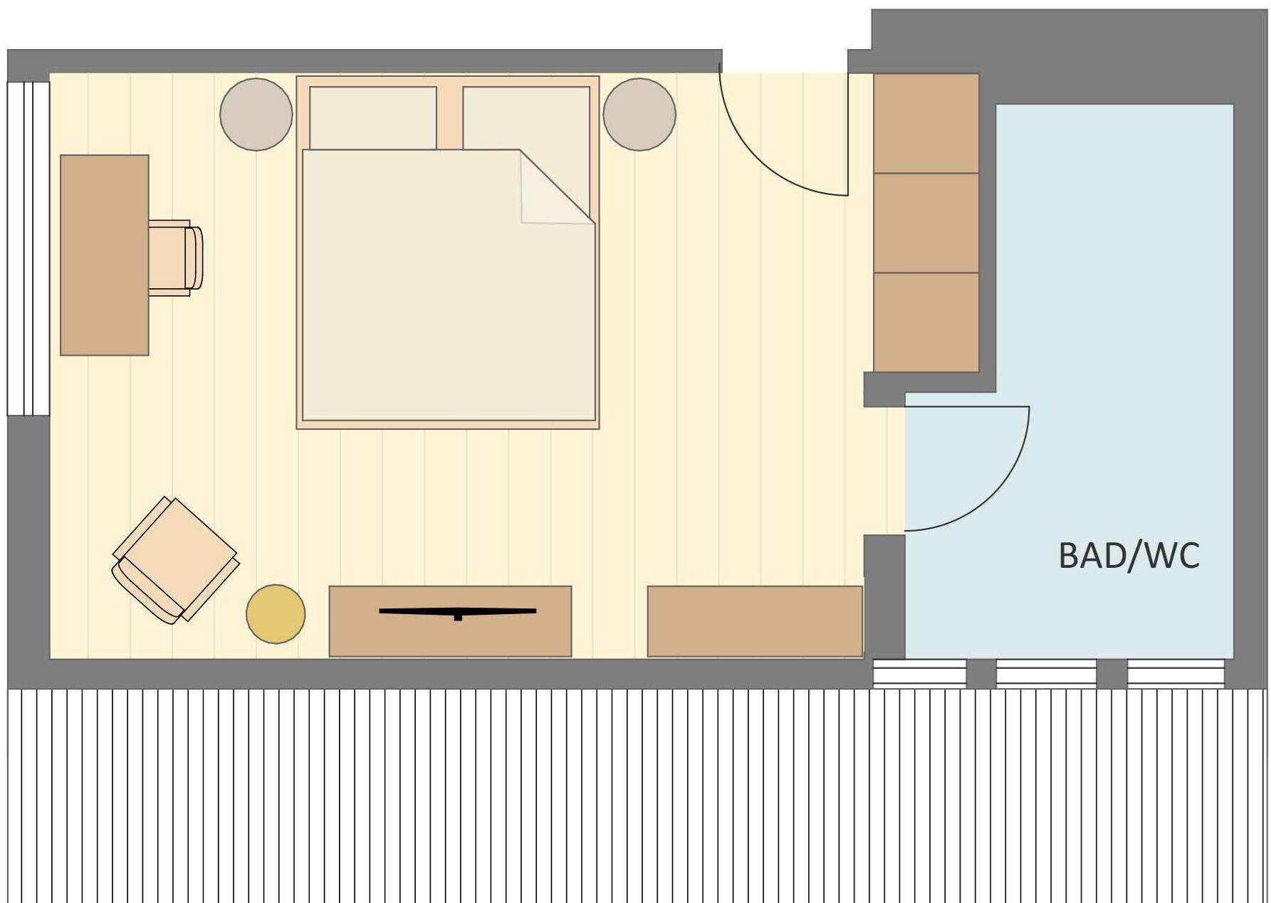 Un dormitorio con cama, mesita de noche y una pequeña zona de estar. Incluye un baño con inodoro, lavabo y ducha. La habitación tiene suelo de madera y ventana.