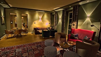 Een moderne woonkamer met een rode bank, gestreepten poefs, en een eethoek met een ronde tafel en stoelen.