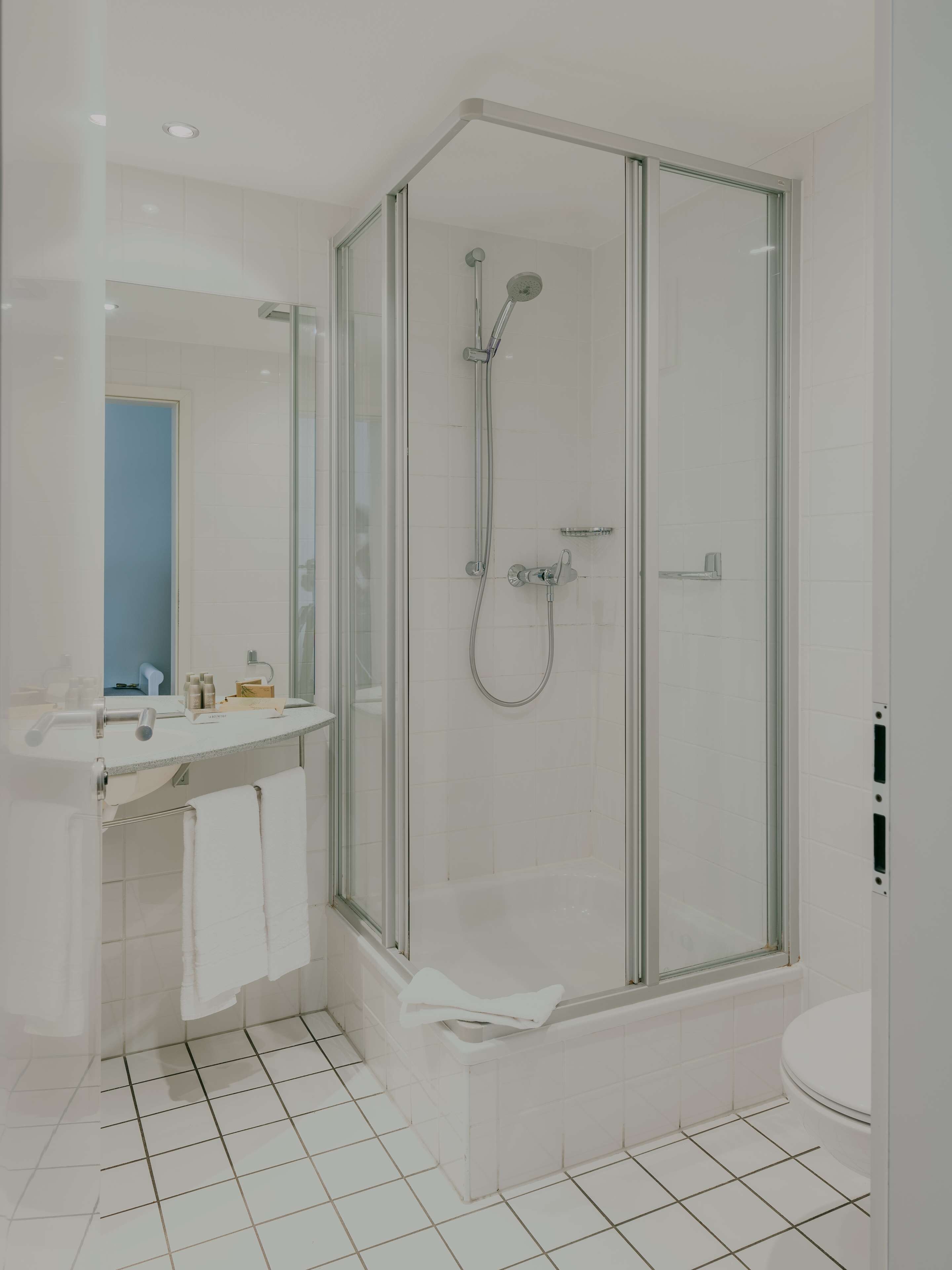 A modern bathroom with a glass-enclosed shower, a white sink, and a toilet.
