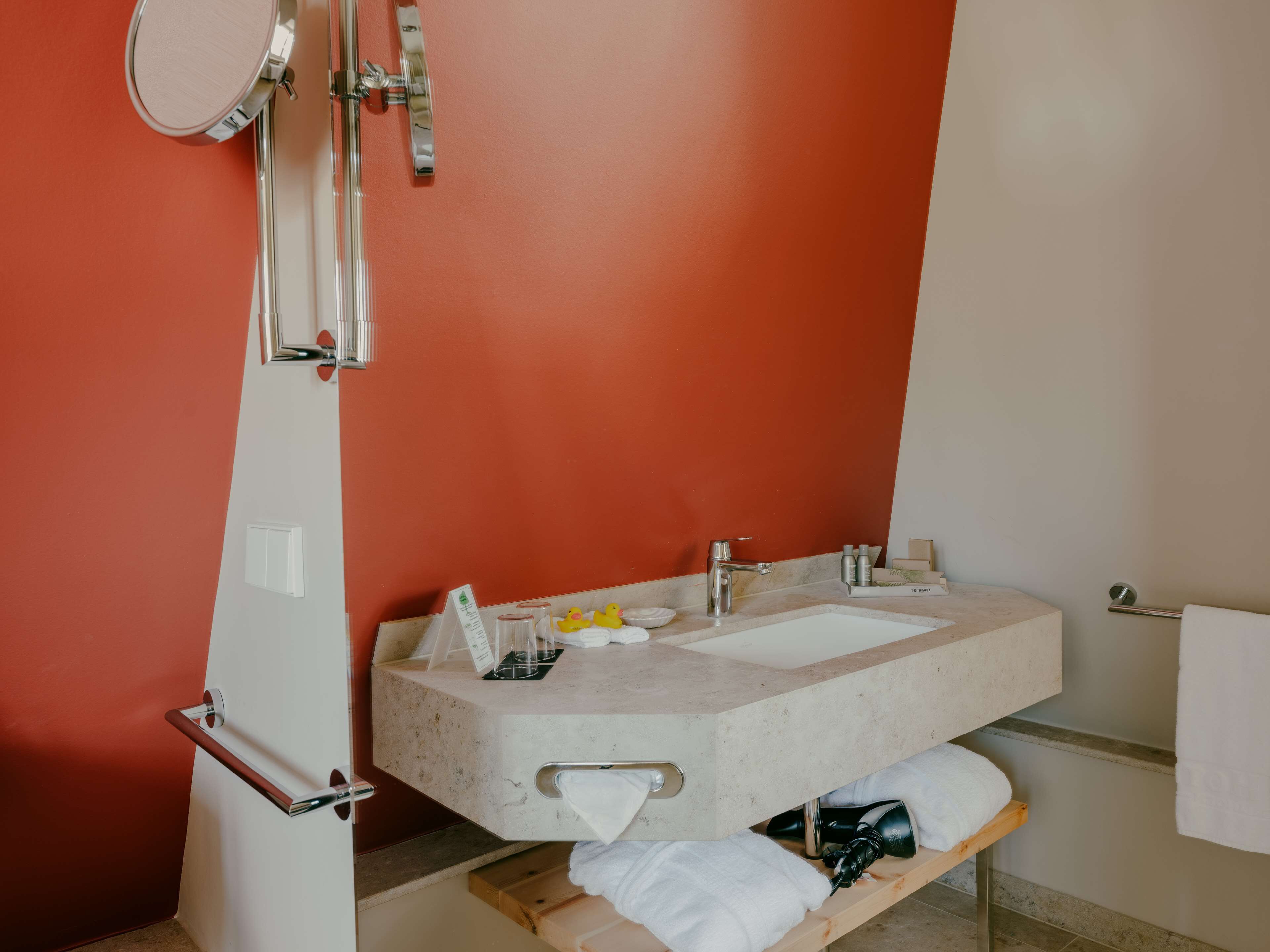 A bathroom with a large mirror, a sink, and a towel rack.