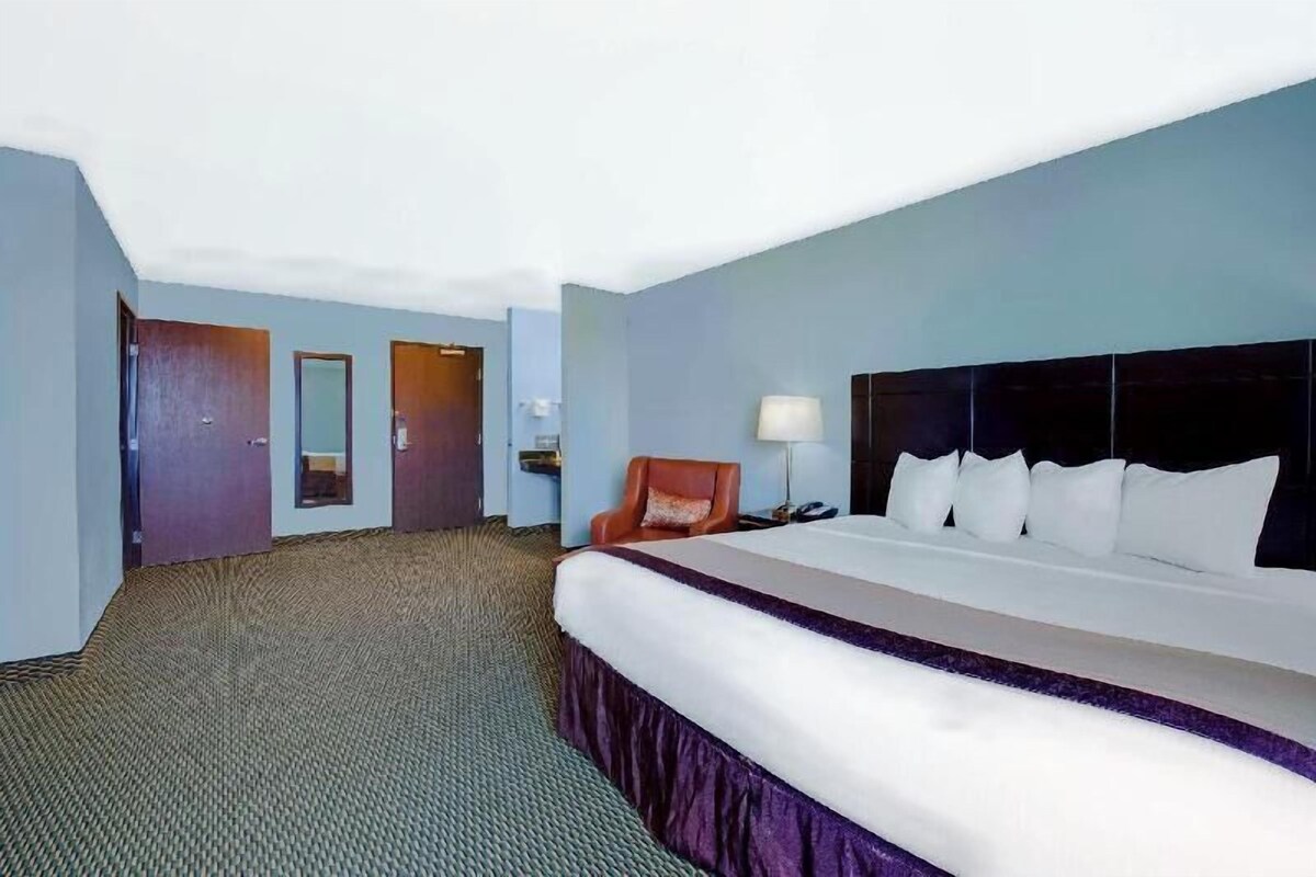 Ein Hotelzimmer mit einem großen Bett, einem Sessel, einem Nachttisch und einem Spiegel.