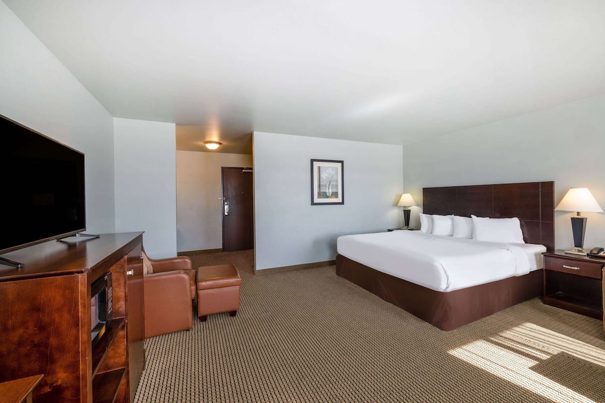 Ein Hotelzimmer mit einem großen Bett, einem Fernseher, einem Schreibtisch und einem Sessel.