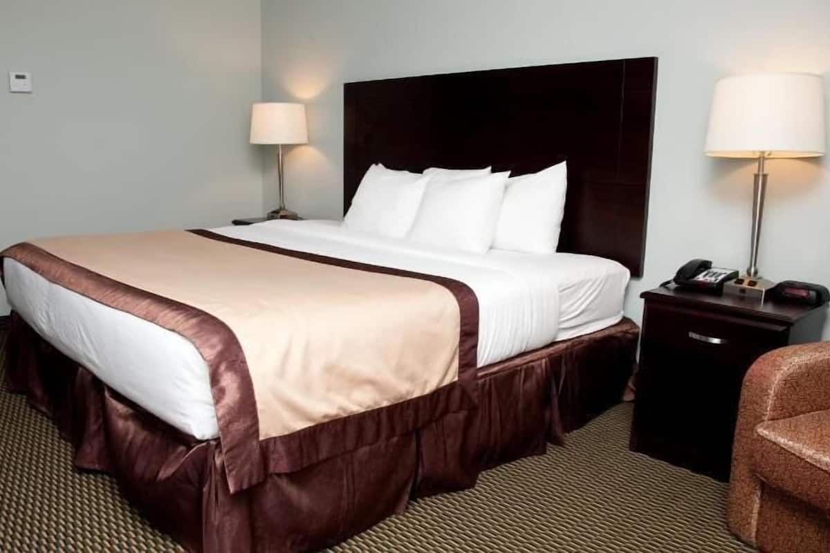 Une chambre d’hôtel avec un grand lit, deux tables de chevet, un bureau et une chaise.