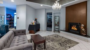 A modern living room with a grey sofa, a small wooden table, and a patterned rug. There is a fireplace with a statue, and a television on a stand. - Baymont by Wyndham Rapid City (Rapid City)