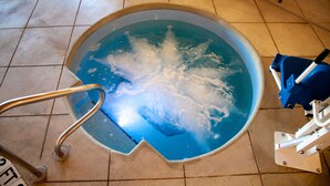 A swimming pool with a metal ladder and a pool cleaning device. - Baymont by Wyndham Rapid City (Rapid City)