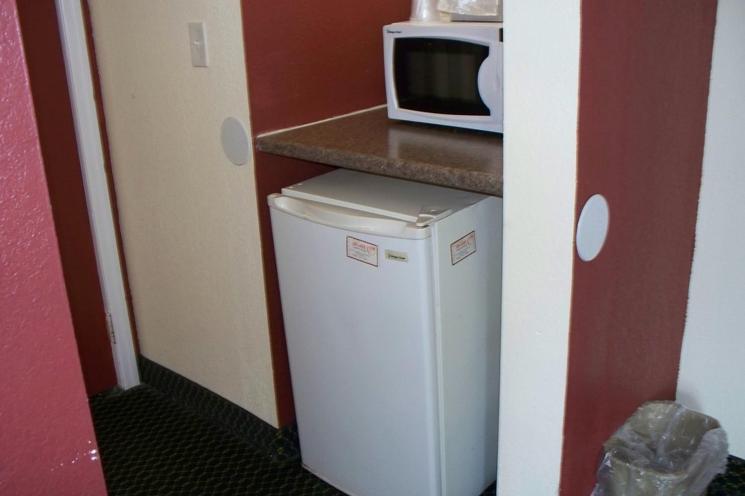 A compact kitchenette with a white refrigerator, a microwave, and a small countertop.