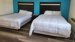 Ein Zimmer mit zwei Betten, jeweils mit Kopfstücken, Holzboden und einer wandfarbenen Teal-Farbe.