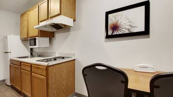 A kitchen with wooden cabinets, a microwave, a stove, and a dining table with chairs.