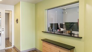 A bathroom with a mirror, a vanity, and a door leading to another room. - WoodSpring Suites College Station (Bryan)