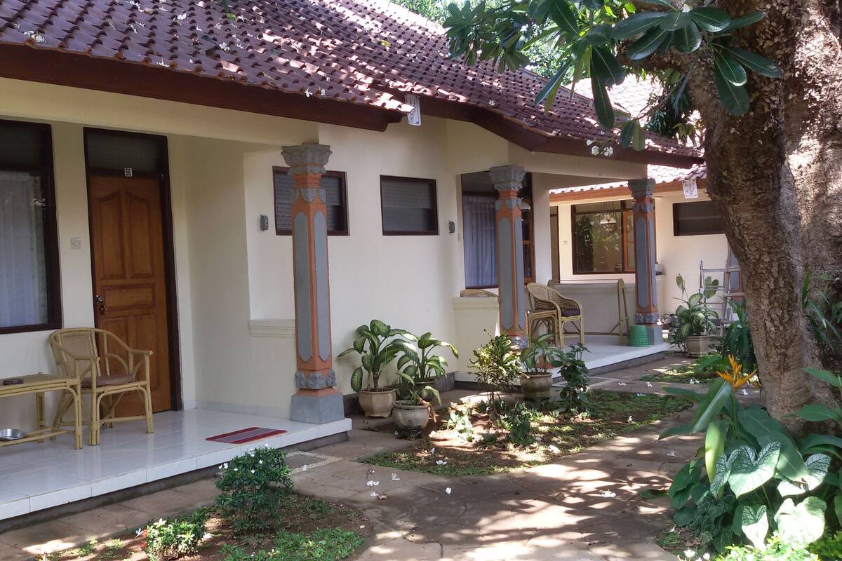 A traditional building with a tiled roof, wooden doors, and a porch area with wicker chairs and potted plants.