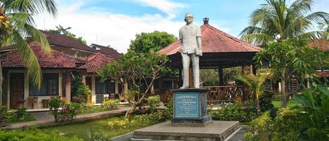 Una estatua en un jardín con edificios tradicionales al fondo.