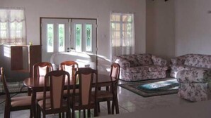 A dining area with a table and chairs, a sofa, and a ceiling fan.