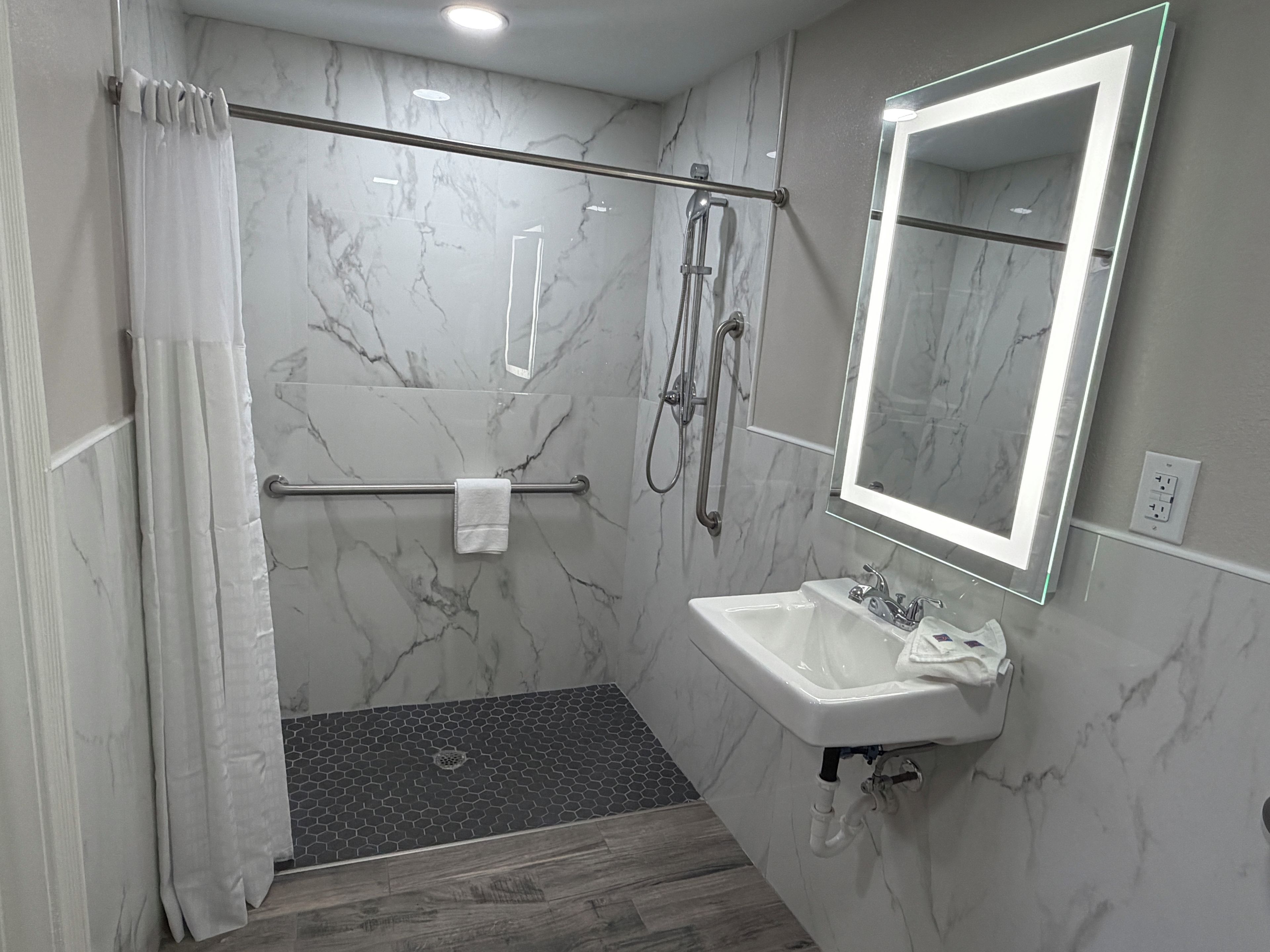 Un baño moderno con ducha, lavamanos, espejo y toallero.