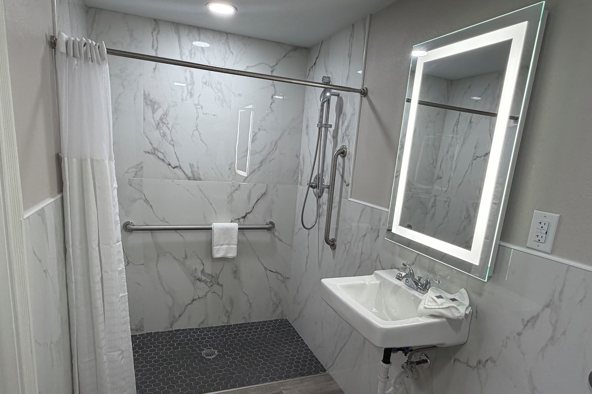A modern bathroom with a shower, a sink, a mirror, and a towel rack.