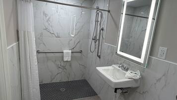 Un baño moderno con ducha, lavamanos, espejo y toallero.