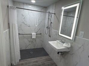 A modern bathroom with a shower, a sink, a mirror, and a towel rack.