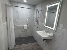 Un baño moderno con ducha, lavamanos, espejo y toallero.