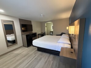 A modern hotel room with a large bed, a desk, a television, and a mirror. - Baymont by Wyndham Newark/Wilmington/Mall Area (Newark)
