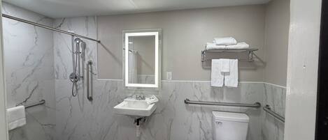 A bathroom with a shower, toilet, sink, and a towel rack.