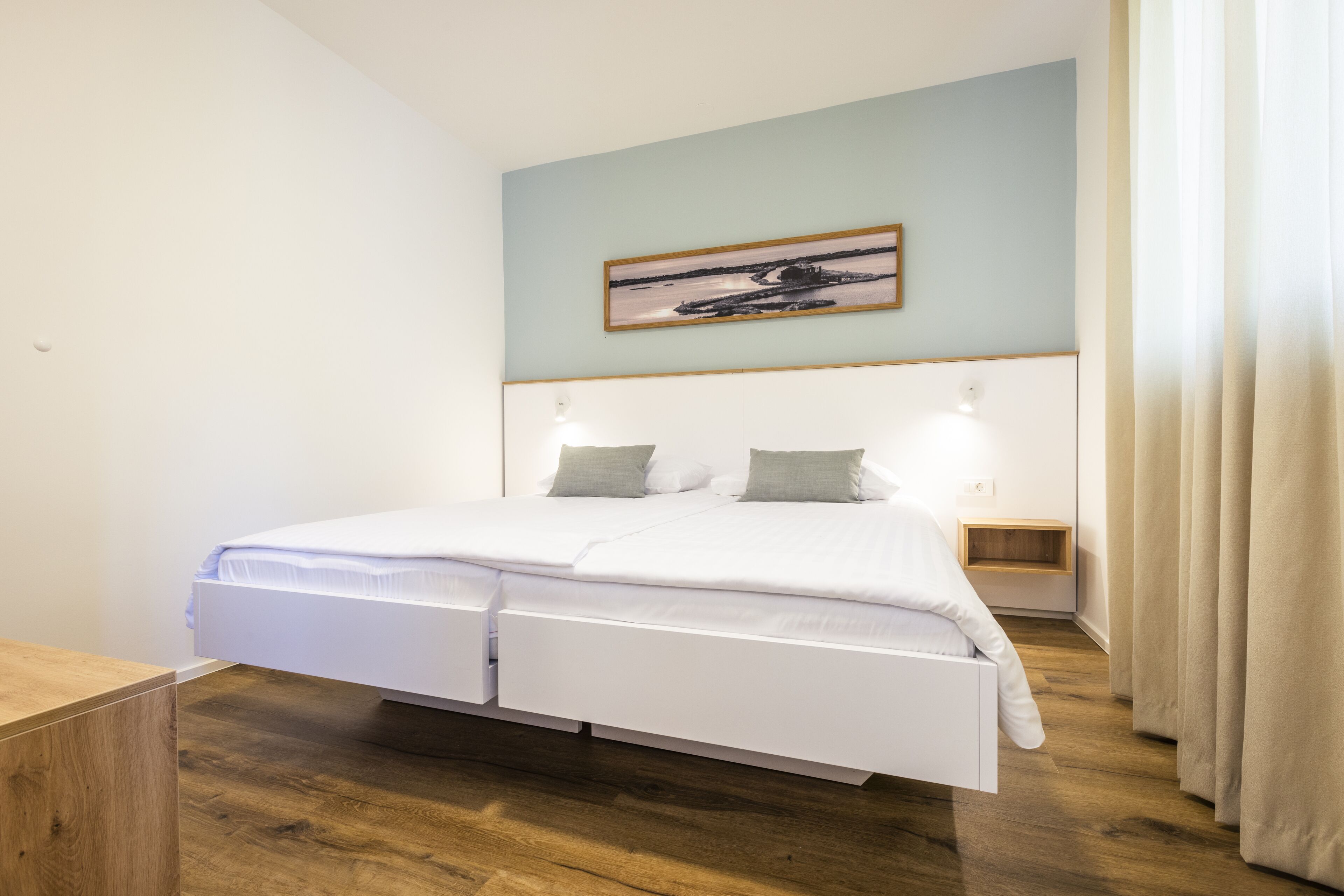 A modern bedroom with a bed, bedside tables, and a painting on the wall.
