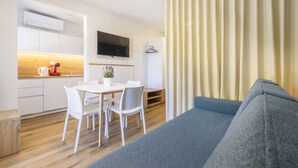 Un espacio habitable moderno y funcional, con kitchenette, comedor y sofá.
