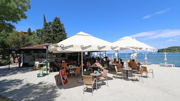 Terraza al aire libre con sombrillas, vista al agua y zona de café.