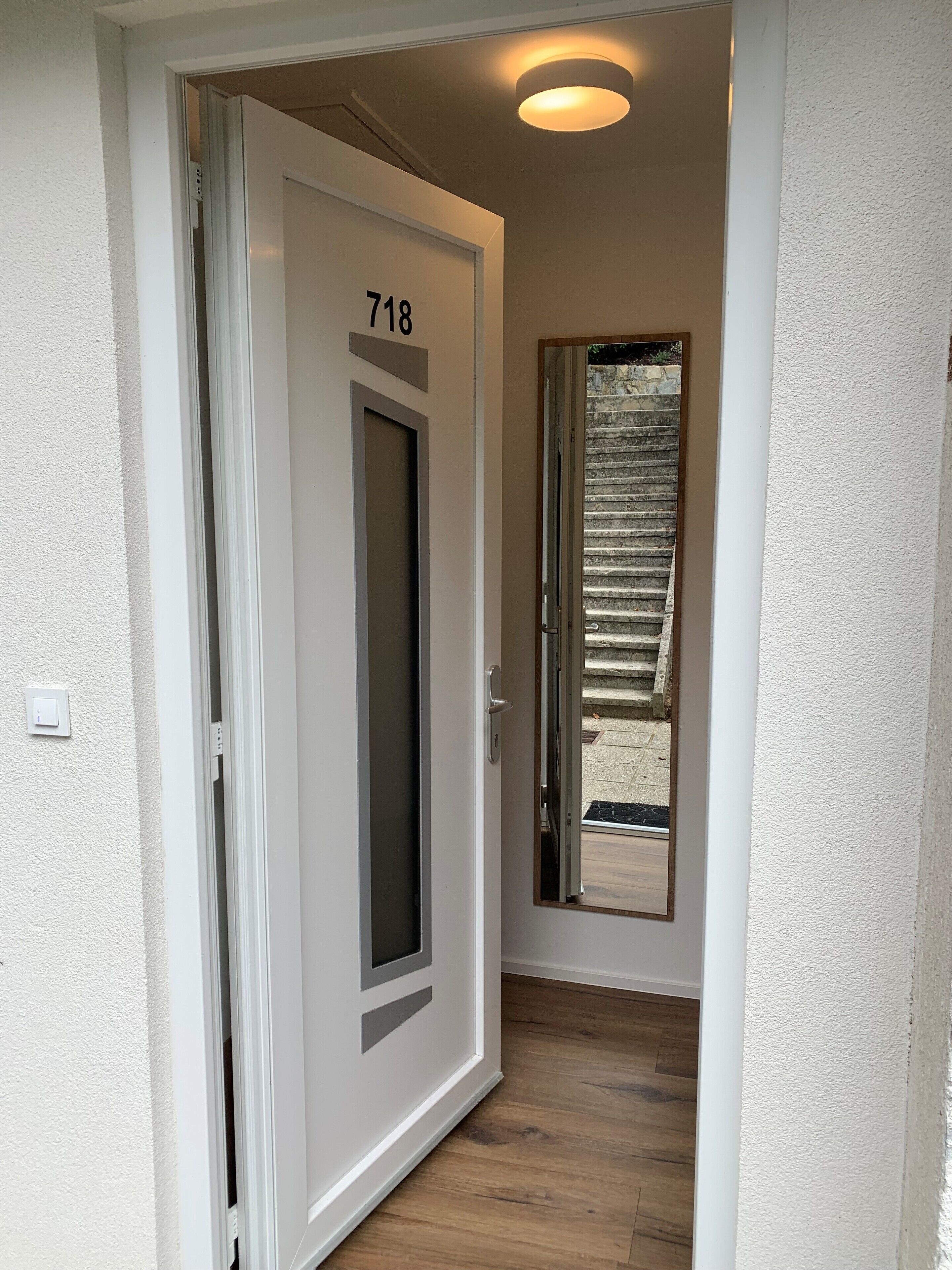 A hallway with a door labeled "718" leading to a room with a window.
