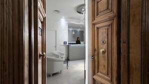 Une porte en bois donne sur une pièce où se trouvent un canapé blanc et une petite table.