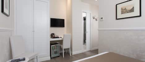A bedroom with a bed, a desk with a chair, a television, and a wardrobe.