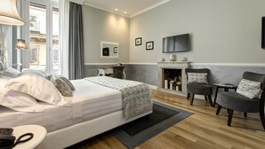 Une chambre d’hôtel moderne dotée d’un grand lit, d’une cheminée, d’une télévision et offrant une vue sur la ville.