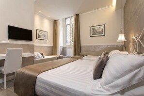 A hotel room with a large bed, a desk, and a TV mounted on the wall.