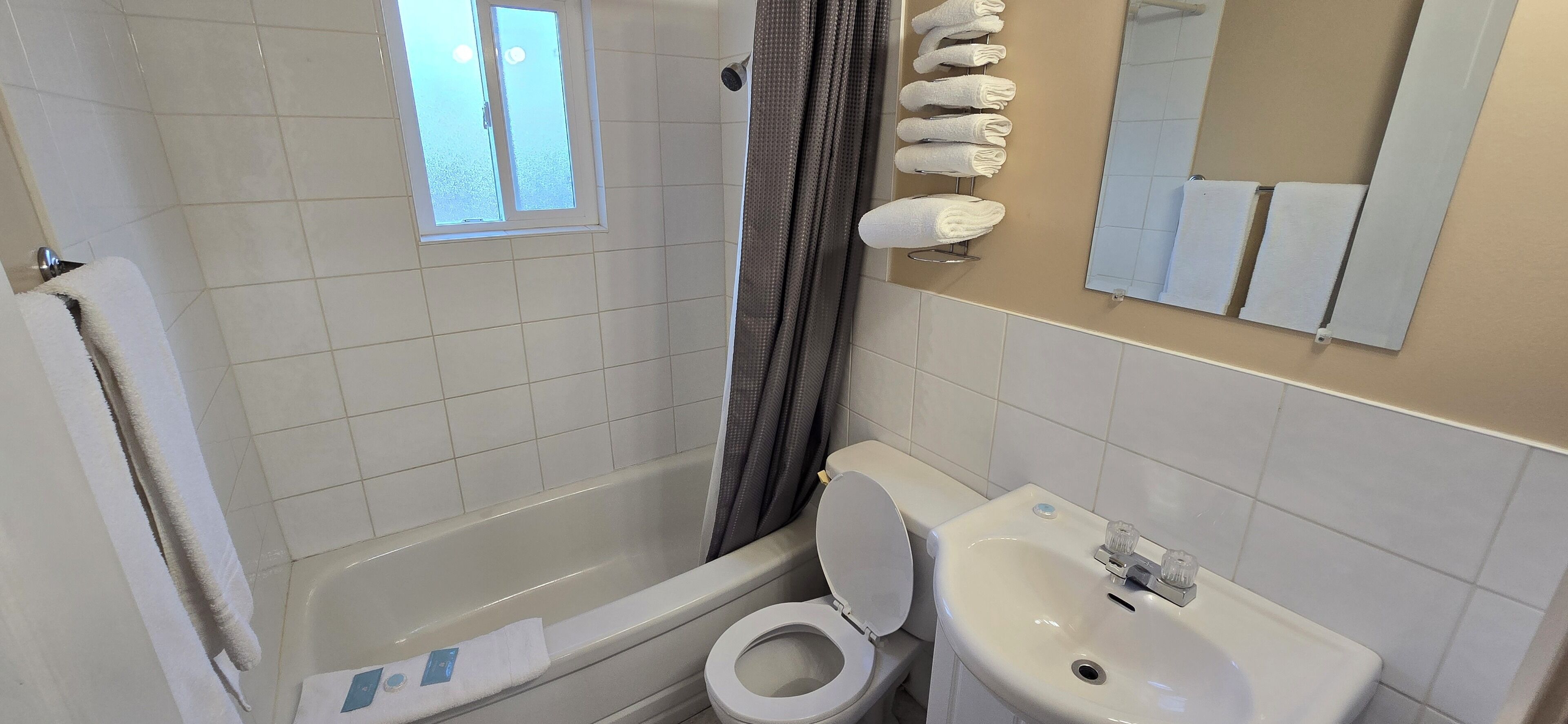 Un baño con bañera, inodoro, lavamanos y ventana.