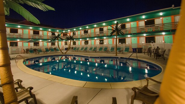 Area piscina con sedie a sdraio e un edificio con numerosi balconi.