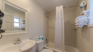 Un bagno con lavandino, WC, vasca e tenda per la doccia.