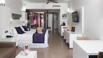 A modern hotel room with a bed, a desk, a chair, a coffee machine, and a TV.
