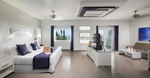 A modern hotel room with a bed, a desk, a sofa, and a view of the ocean.