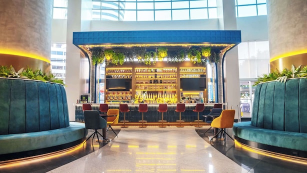 Un espace bar moderne doté d’un comptoir, de sièges et d’une grande fenêtre.