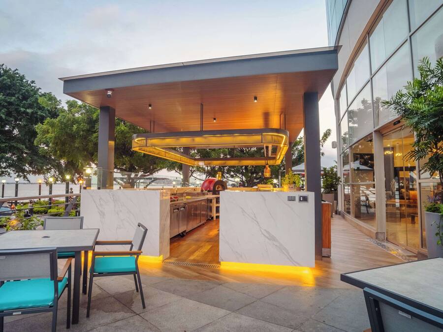 An outdoor dining area with tables and chairs, a covered seating area, and a view of the building's interior.