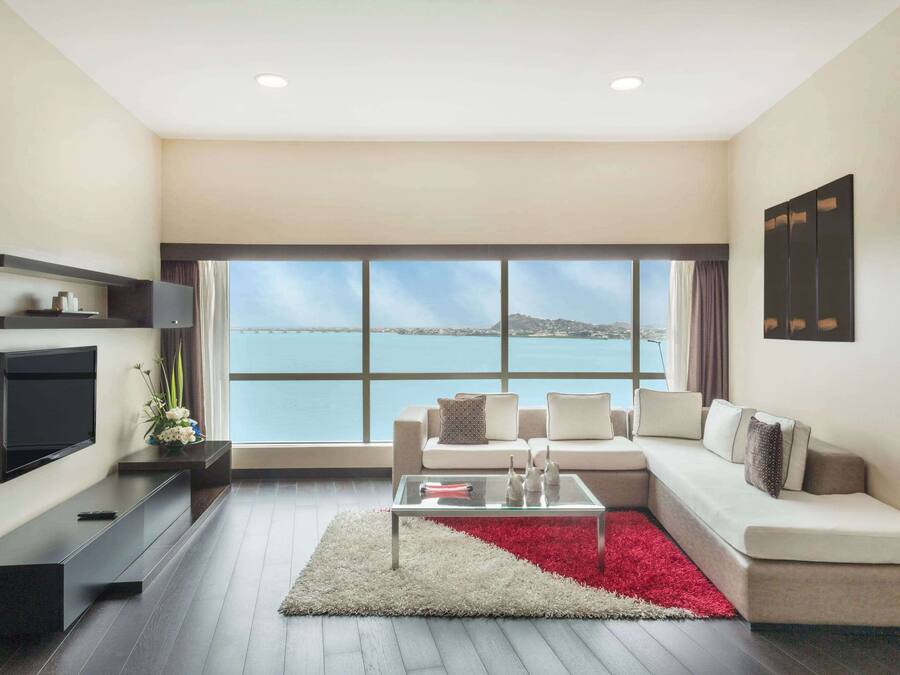 A modern living room with a large window, a flat-screen TV, a sofa, and a coffee table.