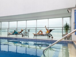 Un espace piscine avec des chaises longues et vue sur l’eau.
