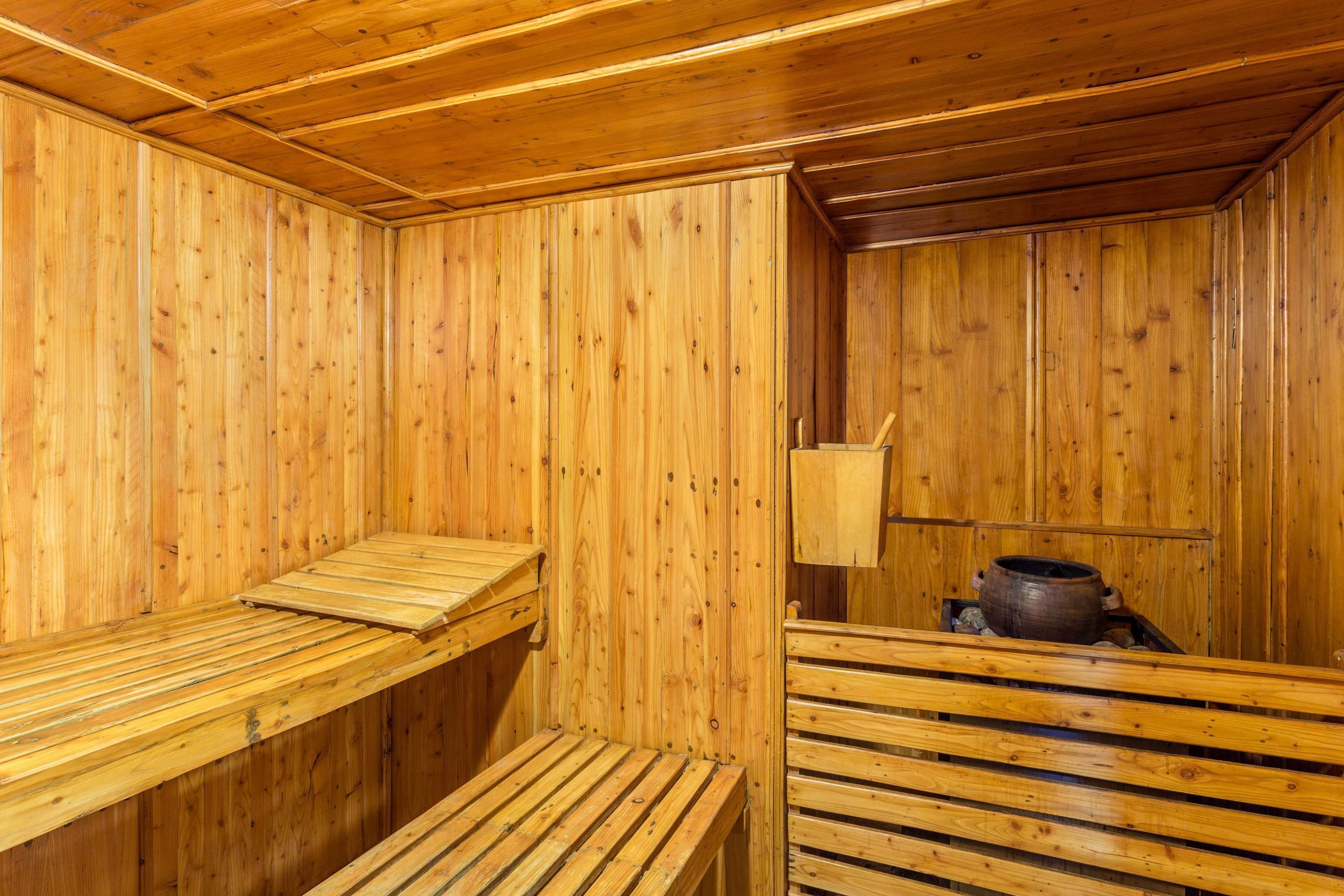 A wooden sauna with benches and a pot on a shelf.