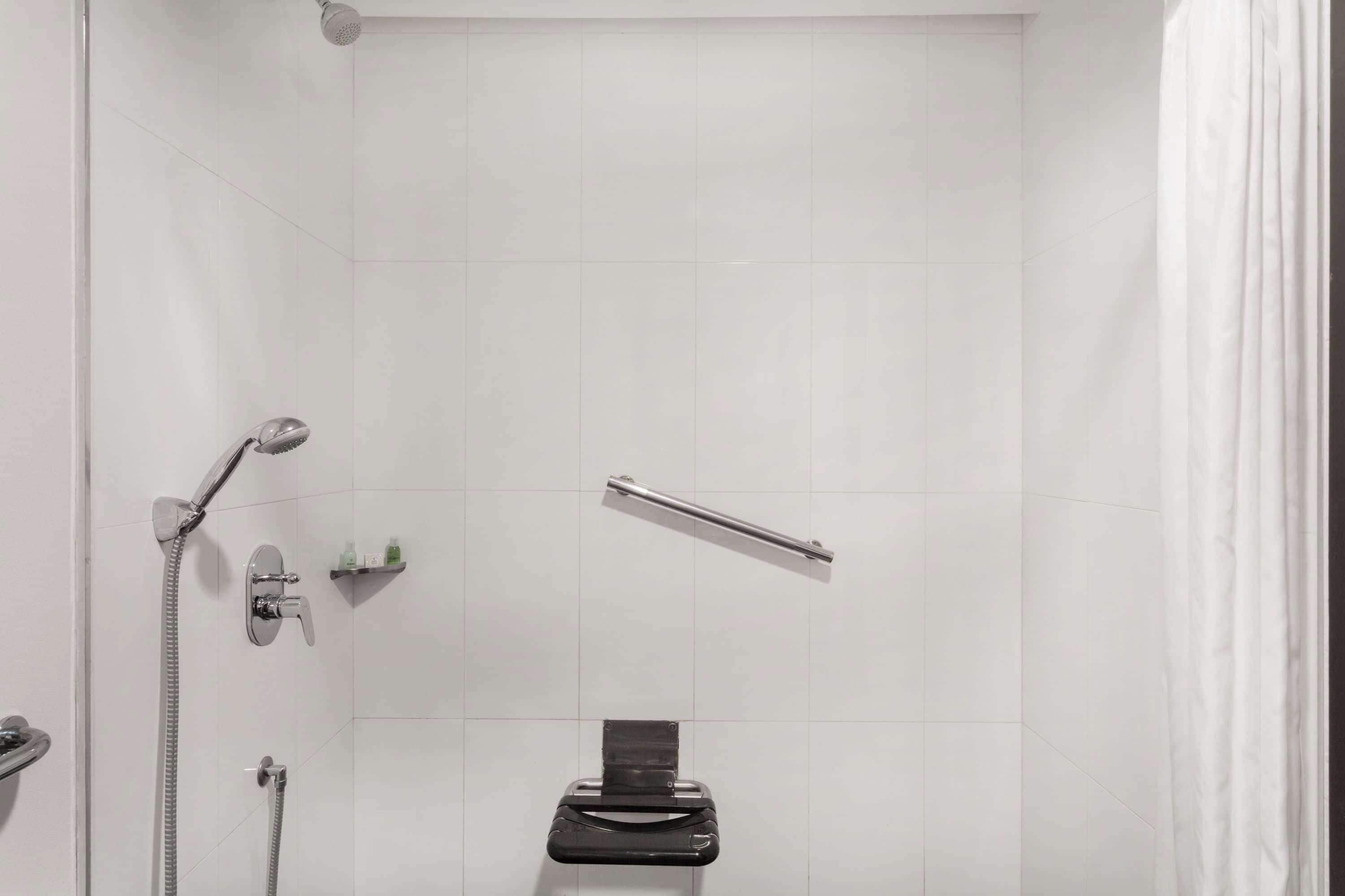 A shower area with a handheld showerhead, a handheld shower attachment, and a towel rack.