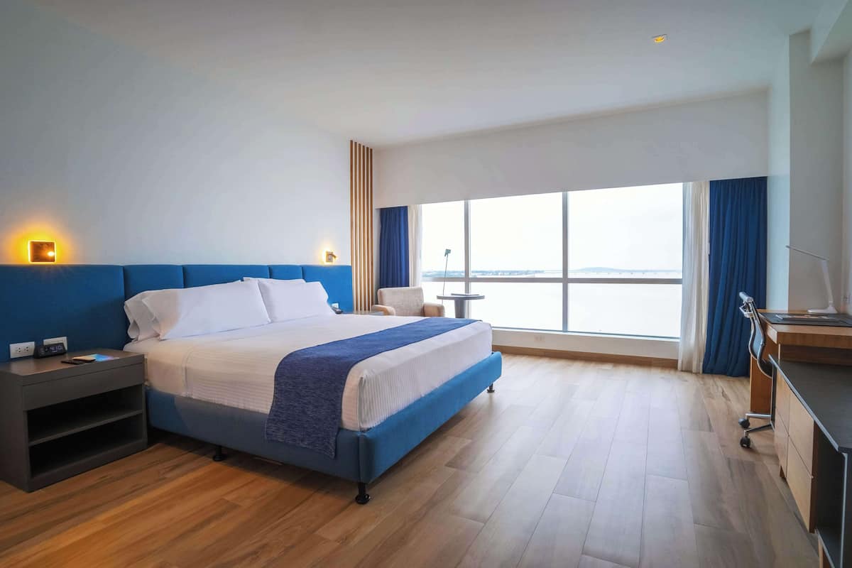 Habitación de hotel moderna con una cama grande, un escritorio y vistas a la ciudad.